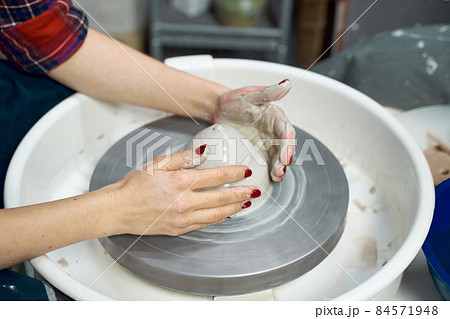 Woman making ceramic pottery, four hands close-up, focus on potters, palms with pottery 84571948
