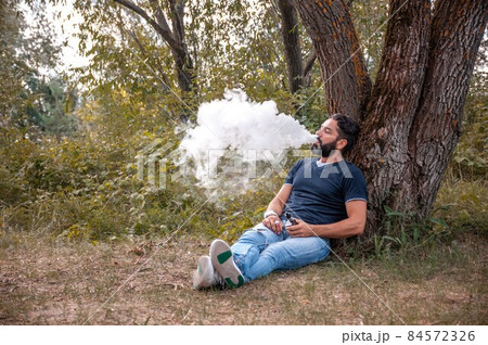 Stylish brutal man smoking an electronic cigarette. Man really likes process of smoking. Stylish brutal man smoking an electronic cigarette. Man really likes process of smoking. 84572326