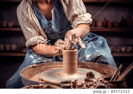 Hands of the master potter and vase of clay on the potter's wheel close-up. Master crock. Twisted potter's wheel. Hands of the master potter and vase of clay on the potter's wheel close-up. Master crock. Twisted potter's wheel. 84572332