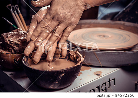 Artisan girl molding a vase of clay on a potter's wheel. Handicraft industry. Close-up. Artisan girl molding a vase of clay on a potter's wheel. Handicraft industry. Close-up. 84572350