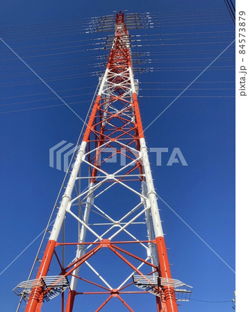 青空に立ちすくむ、赤白の電気の鉄塔です。 84573879
