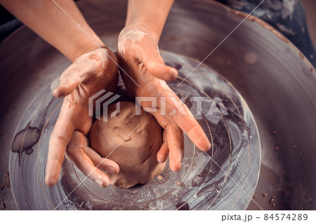 Potter master woman at his wheel creating a new masterpiece. National craft. Close-up. 84574289