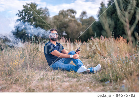 Confident smoker vaping an e-cigarette. Vaping concept. Confident smoker vaping an e-cigarette. Vaping concept. 84575782