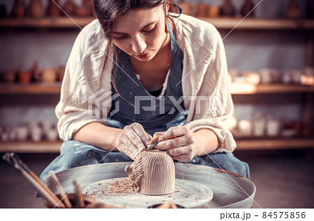 Master-ceramist creates a clay pot on a potter's wheel. Hands of potter close up. Ancient craft and pottery handmade work Master-ceramist creates a clay pot on a potter's wheel. Hands of potter close up. Ancient craft and pottery handmade work 84575856