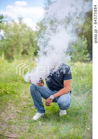 Modern man enjoying an e-cigarette on the forest floor. The man smokes. 84575884