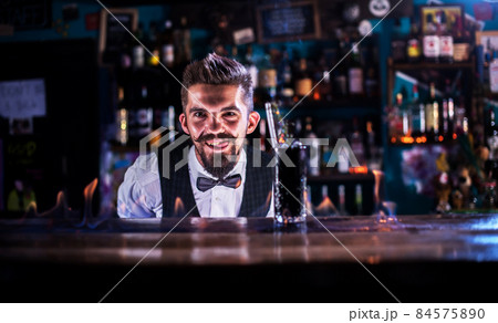 Charismatic Female bartender demonstrates the process of making a cocktail at bar 84575890