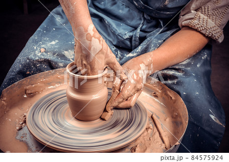 Potter's hands and potter's wheel. Close-up. 84575924