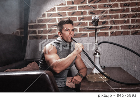 Young fellow smoking shisha in nightclub. Young fellow smoking shisha in nightclub. 84575993