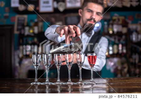 Young bartender demonstrates the process of making a cocktail at the night club Young bartender demonstrates the process of making a cocktail at the night club 84576211