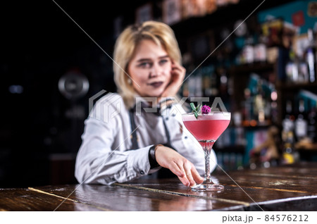 Young girl barman demonstrates his professional skills while standing near the bar counter in bar Young girl barman demonstrates his professional skills while standing near the bar counter in bar 84576212