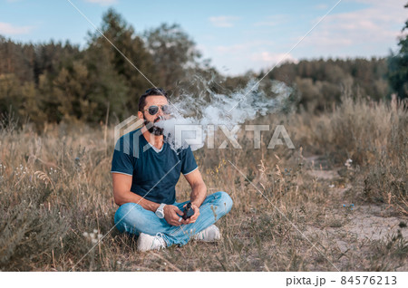 Brutal vape man blows up a couple an electronic cigarette in the outdoors. Electronic cigarette as alternative to tobacco. Brutal vape man blows up a couple an electronic cigarette in the outdoors. Electronic cigarette as alternative to tobacco. 84576213