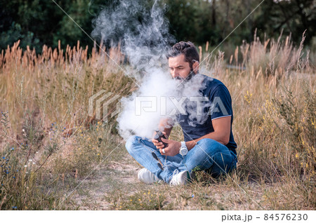 Modern man enjoying an e-cigarette. Man really likes process of smoking. Modern man enjoying an e-cigarette. Man really likes process of smoking. 84576230