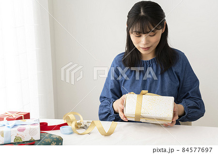 ラッピングしたプレゼントにリボンをかける女性 84577697