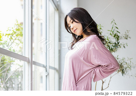 部屋着を着てリビングの窓際に立つ体調不良の女性 部屋着を着てリビングの窓際に立つ体調不良の女性 84579322