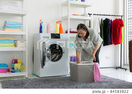 Senior woman preparing the wash cycle. Washing machine, hands and clothes. 84583822