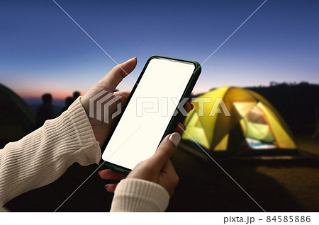 Young woman using smart phone near camping tent in the evening. 84585886