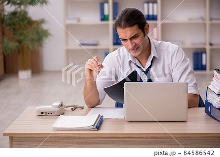 Young male employee and a lot of work in the office 84586542
