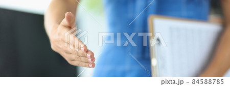Woman holding documents and stretching out her hand for handshake closeup Woman holding documents and stretching out her hand for handshake closeup 84588785
