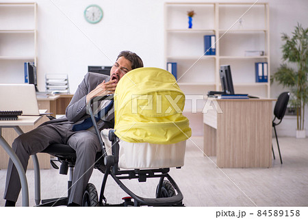 Young male employee looking after new born at workplace Young male employee looking after new born at workplace 84589158