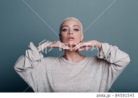 Millenial young woman with short blonde hair portrait doing face yoga self facebuilding massage for skin. Millenial young woman with short blonde hair portrait doing face yoga self facebuilding massage for skin. 84591545