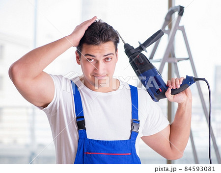 Young worker with hand drill Young worker with hand drill 84593081