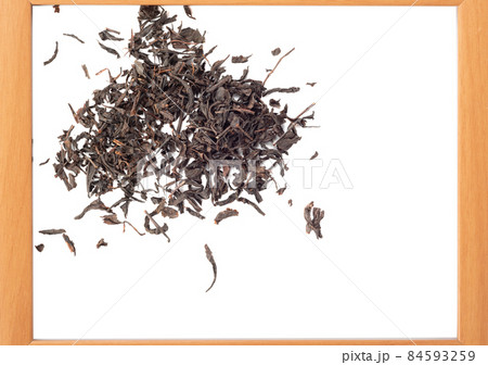 Dry tea leaf scattered on a white background in a wooden frame. Dry tea leaf scattered on a white background in a wooden frame. 84593259