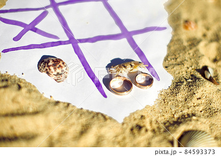 Tic Tac Toe and wedding rings on the beach. Wedding in the tropics concept Tic Tac Toe and wedding rings on the beach. Wedding in the tropics concept 84593373