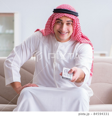 Arab man watching sport football at tv 84594331