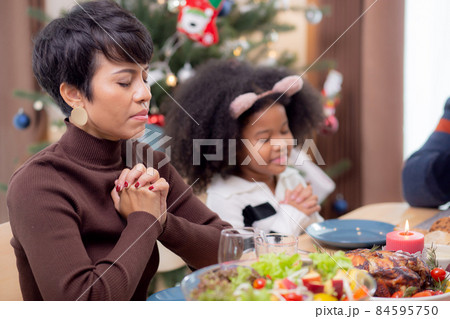 Happy African family holding hands and praying dinner on thanksgiving eve day together. Happy African family holding hands and praying dinner on thanksgiving eve day together. 84595750
