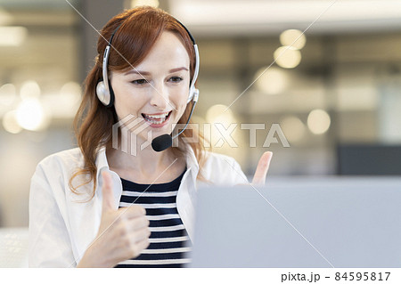パソコンに向かっていいねをするヘッドセットをつけた外国人女性 84595817