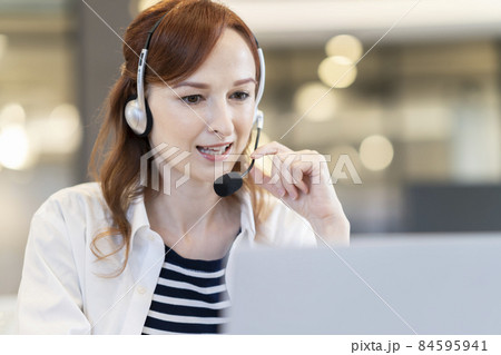 パソコンに向かって話すヘッドセットをつけた外国人女性 84595941