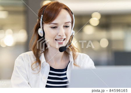 パソコンに向かって話すヘッドセットをつけた外国人女性 84596165