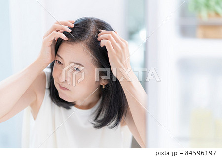 鏡を見て薄毛にショックを受けるミドルエイジの女性 84596197