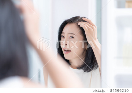 鏡を見ながら髪のチェックをするミドルエイジの女性 84596210