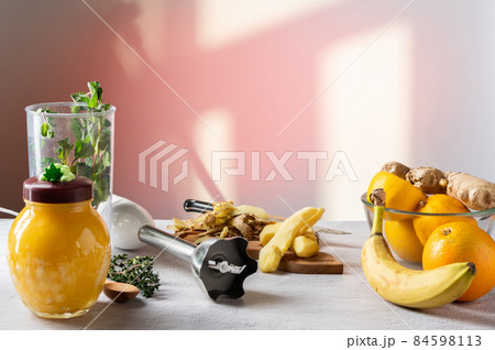 Peeled ginger root on the table. Fruit and honey on the table. Shadow from the window. 84598113