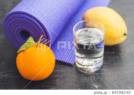 Yoga mat, water, orange and mango on a wooden background. Equipment for yoga. Concept healthy lifestyle, diet and sport. Copy space. Selective focus 84598240