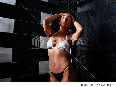Portrait of a beautiful sexy blonde European woman with tanned skin taking shower in spa bathroom, enjoying the freshness and coolness of water 84601847