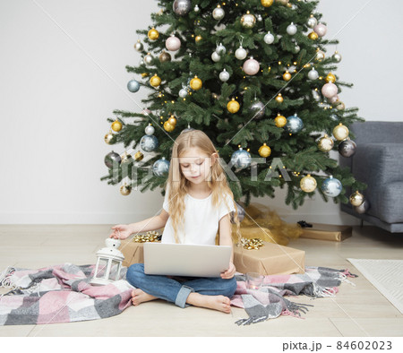 Little Girl plays near the Christmas tree. 84602023