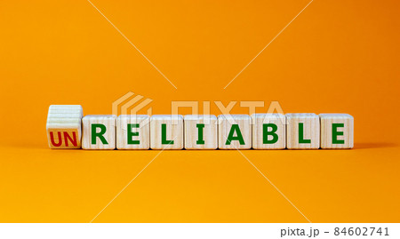Unreliable or reliable symbol. Turned wooden cubes and changed the word unreliable to reliable. Beautiful orange background, copy space. Business and unreliable or reliable concept. 84602741