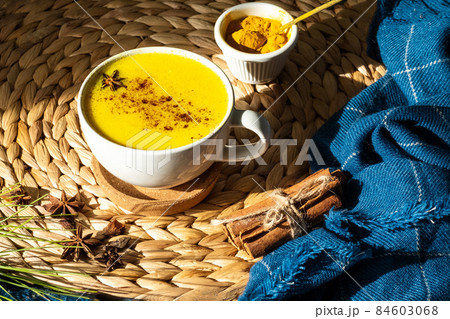 Top down view of Golden milk or Turmeric Latte cup on a straw plate stand. 84603068