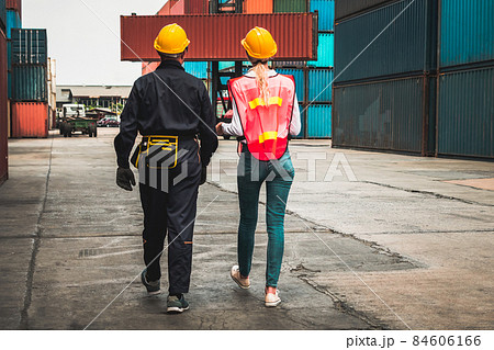 Industrial worker works with co-worker at overseas shipping container yard 84606166