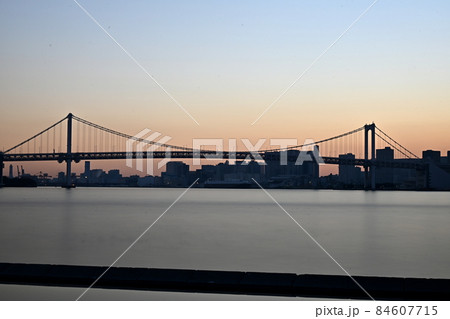 東京湾レインボーブリッジの夕景　ライトアップ前の控えめな色合い　長時間露光　波の見えない滑らかな海面 84607715
