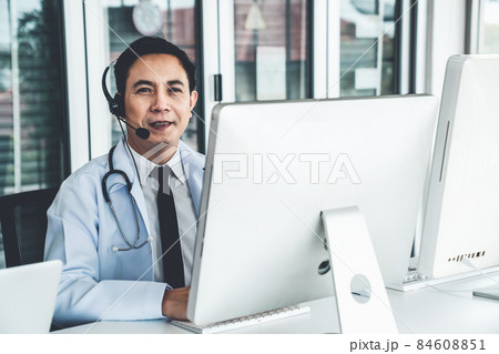 Doctor wearing headset talking actively on video call in a clinic or hospital . 84608851