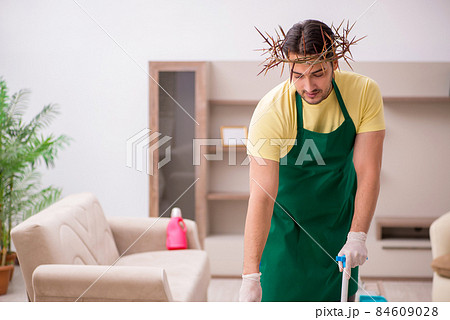 Young male contractor wearing prickly wreath on head cleaning th 84609028
