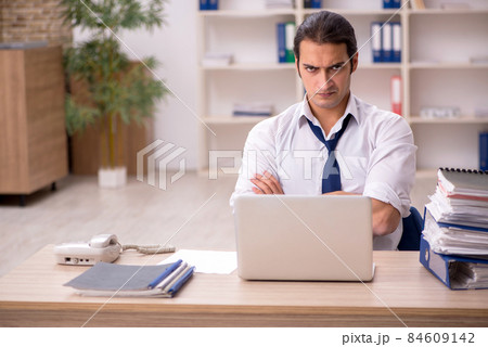 Young male employee and a lot of work in the office 84609142
