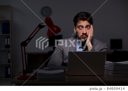 Young male employee working late in the office 84609414