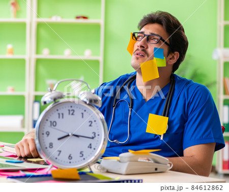 Young doctor sitting in hospital with many conflicting prioritie Young doctor sitting in hospital with many conflicting prioritie 84612862
