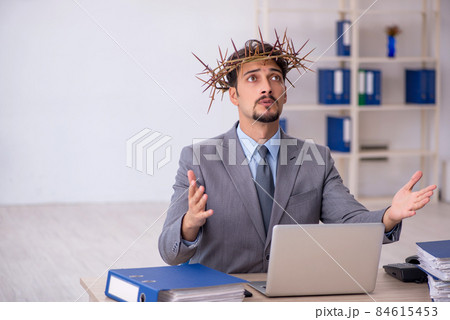 Young male employee wearing prickly wreath on head Young male employee wearing prickly wreath on head 84615453