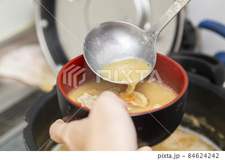 豚汁を入れる女性の手元 84624242