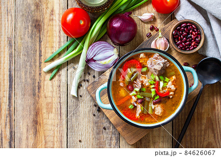 Traditional English thick soup with beef, beans and vegetables on a wooden table. Hot dinner or lunch. Top view flat lay. Copy space. 84626067